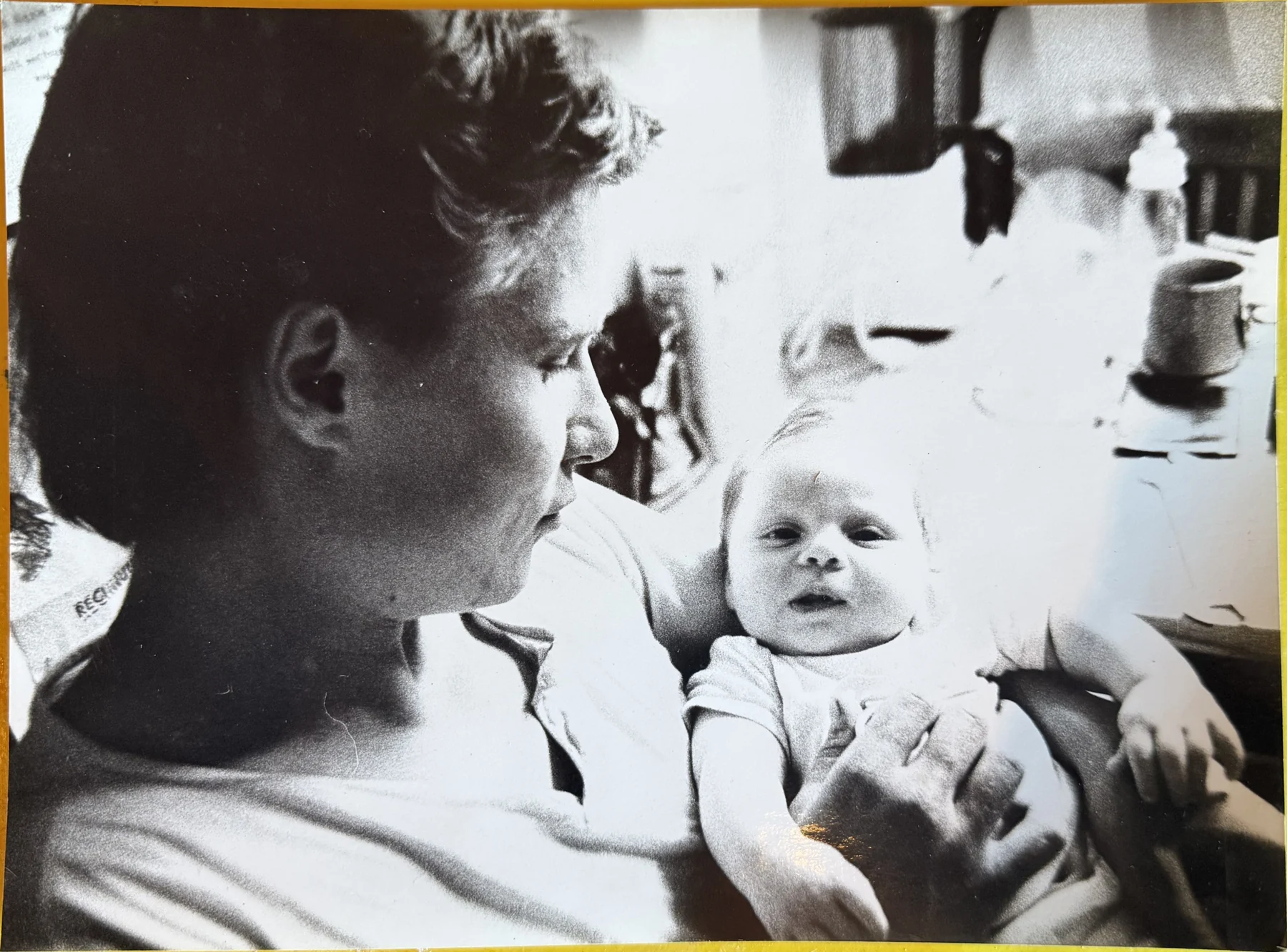 Michael Plötz mit seinem Sohn Daniel Plötz in einem Innenraum. Michael ist im Profil zu sehen; Daniel blickt als Säugling in die Kamera.